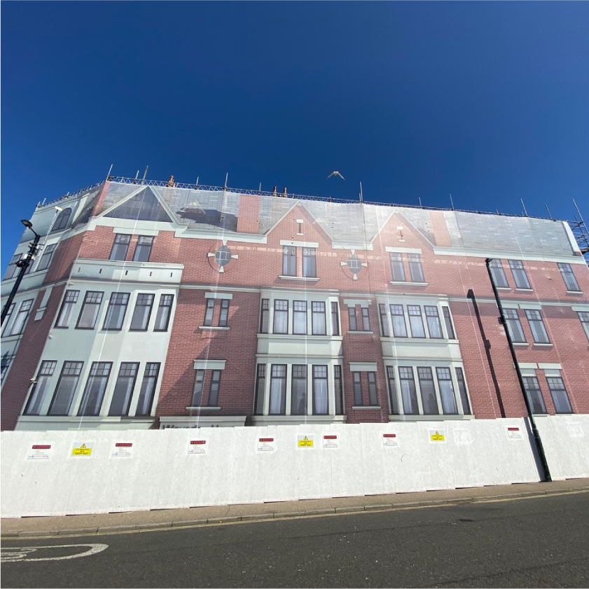 Large mesh banner on construction site made to look like multi-story building